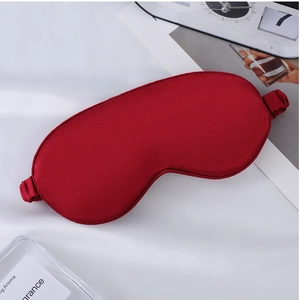 Close-up of red silk sleep mask with elastic strap on a soft white background