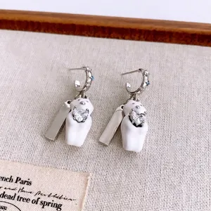 Elegant bear earrings set with heart-shaped zircon and silver metal on a beige texture