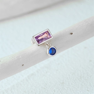 Macro shot of silver stud earring with opal and bicolored gem on a textured branch