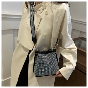 Detail of silver rhinestone bucket bag with black leather trim and woven strap