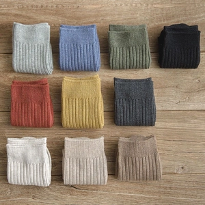 Flat lay of ribbed cotton mid-tube socks in ten assorted vintage colors on a wood surface