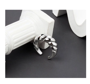 Close-up of a silver croissant twisted ring on a white marble pillar with a gray background