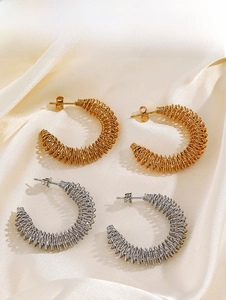 Détail de boucles d'oreilles en C dorées et argentées sur fond de soie