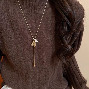Detail of French vintage gold necklace with white petal pendant and delicate long tassels