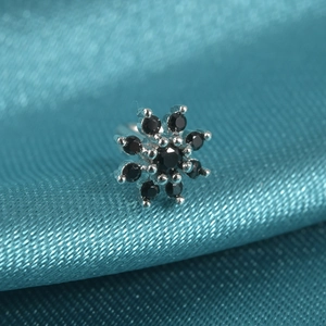Macro shot of silver flower nose stud with black zircon stones on blue silk fabric