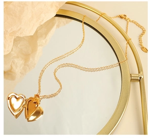 Detail of a vintage gold heart locket necklace displayed on a decorative mirror frame