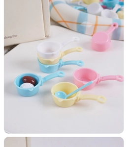 Makroaufnahme bunter 4cm Puppenhaus-Minipotts und Schöpflöffel mit winzigen Spielzeugeiern