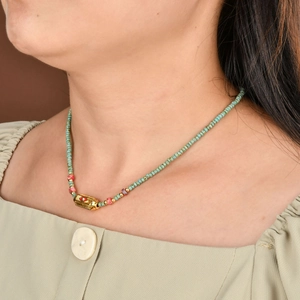Close-up of turquoise beaded necklace with engraved gold evil eye pendant on a model