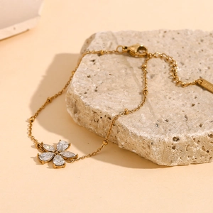 Detail eines 18K vergoldeten Blumenarmbands mit Zirkonia auf Stein-Hintergrund