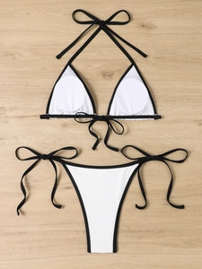 Flat lay of a ribbed black and white triangle bikini set with lace-up ties on wood