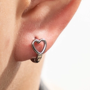 Polished stainless steel hollow heart-shaped hoop earrings worn by a model on white background