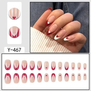 Faux ongles French manucure rouges avec motifs de cœur et finition brillante