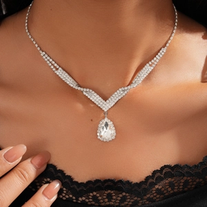 Macro shot of a sparkling silver V-shaped necklace with a pear-cut drop zircon pendant