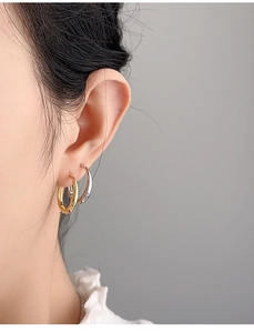 Close-up detail of silver and gold hoop earrings worn on ear for minimalist jewelry style