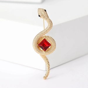 Detailed close-up of golden cobra brooch with red gemstone and intricate metal textures