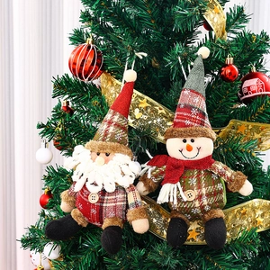 Detalle de adornos navideños de tela escocesa con Papá Noel y un muñeco de nieve en el árbol.