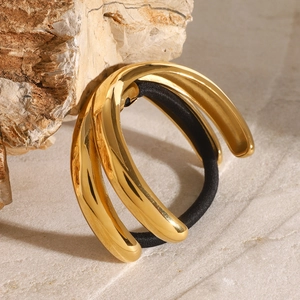 Nahaufnahme eines minimalistischen goldenen Haargummis aus Metall auf hellem Naturstein