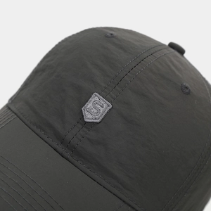 Close-up of nylon baseball cap fabric texture and shield-shaped S letter embroidery