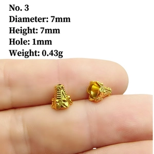 Macro detail of 7mm golden alloy bead showing engraved texture and scale on finger