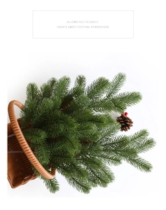Close-up of artificial pine needles with cones and red berries in a brown woven basket