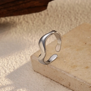 Minimalist silver wave open ring in stainless steel displayed on a natural stone base
