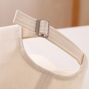 Detail of beige cotton baseball cap with adjustable metal buckle and twill fabric