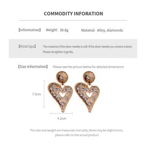 Detailed view of gold heart drop earrings with white rhinestones and size measurements