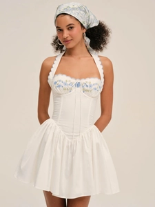 Detail of white corset mini dress with blue floral embroidery and scalloped neckline trim