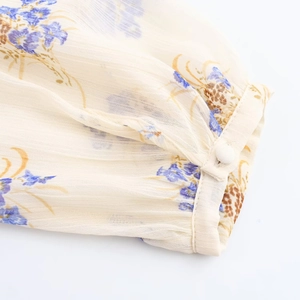 Dettaglio ravvicinato dei polsini di una camicia in chiffon floreale con bottoni e cuciture