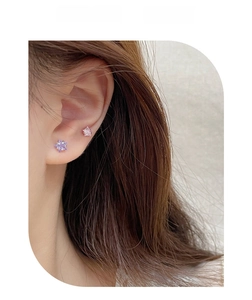 Close-up of sparkling star-shaped zircon stud earrings in purple and pink tones