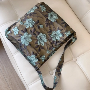 Dettaglio del tessuto jacquard floreale verde scuro con texture satinata sulla borsa