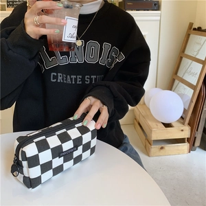 Close-up of a checkered pencil case featuring a black zipper pull and logo detail