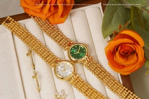 Detail of luxury gold quartz watches with emerald green and ivory dials and beaded bands