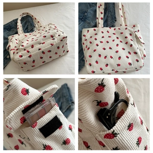 Detail view of white corduroy tote bag with strawberry print and velcro pocket closure
