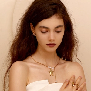 Detail of 18K gold starfish pendant necklace and matching pearl jewelry set on model
