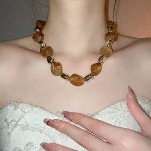 Retro acrylic marbled amber beads necklace with gold metal accents on model neck