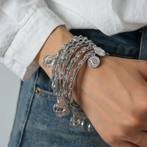 Detail of silver layered bracelet set with vintage coin charms on a female wrist