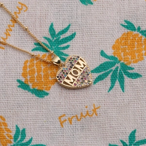 Detail of gold heart pendant with MOM lettering and colorful cubic zirconia inlay