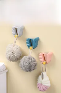 Three thumb-shaped wall hooks in blue pink and grey holding mesh shower loofahs