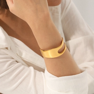 Elegant 18K gold plated asymmetric open cuff bracelet in stainless steel on a female wrist