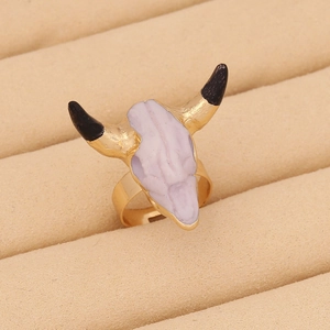 Detail of bohemian bull skull ring in gold with purple enamel in a velvet jewelry box