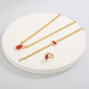 Detail of gold jewelry set with red teardrop pendants on a white circular display stand