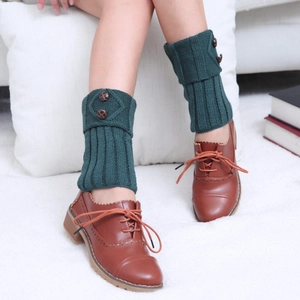 Detail of dark green knit leg warmers with brown buttons on a diamond patterned cuff