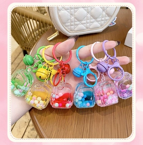 Detail of colorful liquid quicksand schoolbag keychains held to show acrylic texture