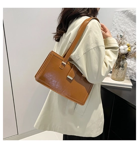Detail view of a vintage brown glossy leather shoulder bag with a stylish metal clasp