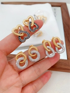 Macro detail of gold plated double-layer cross earrings with black and white zircon