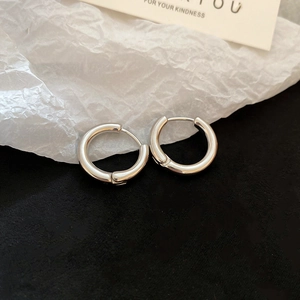 Detail of silver huggie hoop earrings with polished mirror finish on a contrast background