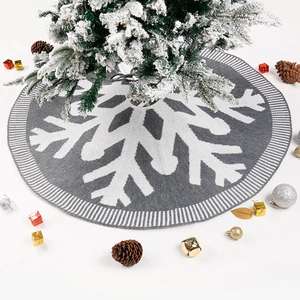 Grey knitted Christmas tree skirt with white snowflake patterns and holiday decorations