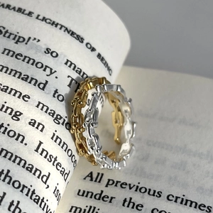 Polished 925 sterling silver chain-link rings in gold and silver finish on a book