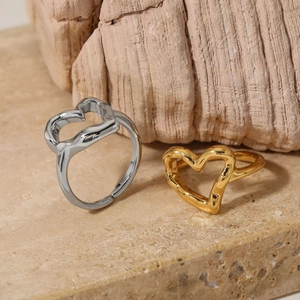 Minimalist hollow heart rings in gold and silver finish on a textured stone surface